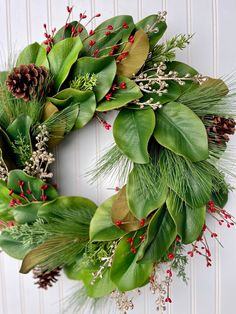 a green wreath with red berries and greenery