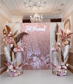 two tall vases filled with flowers and feathers on top of a white carpeted floor