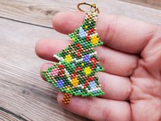 a hand holding a beaded christmas tree keychain