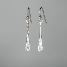 "These earrings are made by hand hammering sterling silver carefully to create an elegant tapered stick. A dimpled hammer texture is applied to the front to add dimension. The earrings are polished to a high reflective shine to catch the light perfectly. These are designed to be comfortable and lightweight. Full of movement and just the right amount of sparkle, these are the perfect everyday earrings! * The total length including the ear wire from top to bottom is 1.5\" (37mm) * The drop from th Classic Hammered Drop Earrings, Hammered Sterling Silver Long Drop Earrings, Elegant Hammered Sterling Silver Teardrop Earrings, Silver Bar Earrings, Stick Earrings, Earrings Everyday, Hammered Sterling Silver, Silver Bar, Silver Dangle Earrings