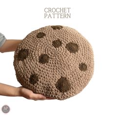 a crocheted round cushion is held in the palm of someone's hand