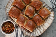 a plate full of sliders next to a bowl of salsa