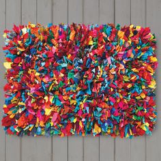 a multicolored area rug is displayed on a wooden wall with wood planks in the background