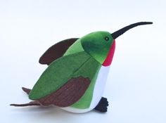 a green and brown bird sitting on top of a white table