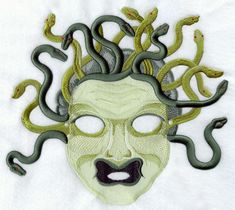 an embroidered mask with green snakes surrounding it