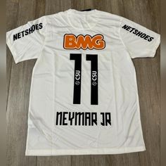 the back of a white shirt with black and orange lettering on it, which reads bmg 11 neymar jr