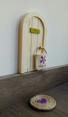 a small basket sitting on top of a wooden table next to a white door with a purple flower