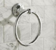 a chrome towel ring on the wall in a white tiled bathroom with black and white tiling