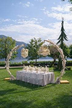 an outdoor table set up with white flowers and greenery for a wedding reception on the lawn