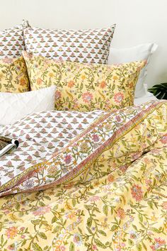 a bed covered in yellow and pink floral comforter with matching pillow cases on it