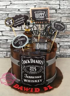 a birthday cake that is decorated with liquor bottles and happy birthday stickers on top