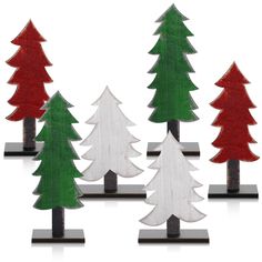 wooden christmas trees are lined up against each other on black and white bases, with red and green pine trees in the background