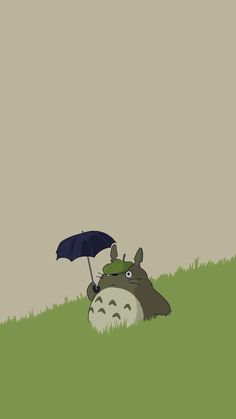 an animal laying on top of a lush green field next to a black and white umbrella