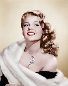 a woman in a black dress and white fur stole with a necklace on her neck