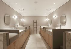 a long row of sinks in a bathroom with mirrors and lights on the wall above them