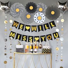 a party with black and gold decorations, silver balloons and streamers on the wall