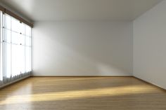 an empty room with white walls and wooden floors, sunlight coming through the window onto the floor