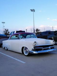 an old white car parked in a parking lot