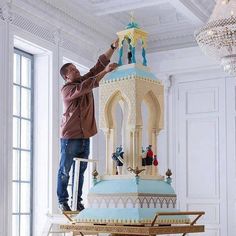 a man standing on top of a giant blue and white cake