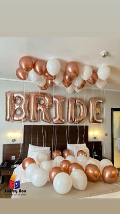 a bed topped with lots of white and rose gold balloons