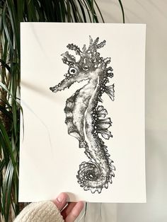 a person holding up a card with a drawing of a sea horse on it's back