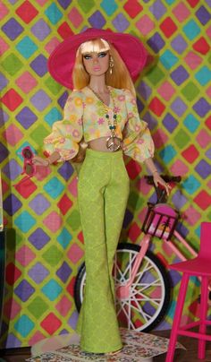 a barbie doll is standing in front of a colorful wall