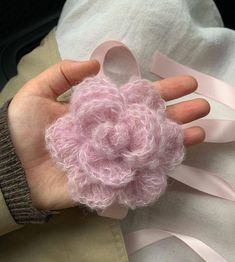 a person is holding a pink flower brooch