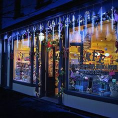 a store front with christmas lights on the windows and decorations hanging from it's windows