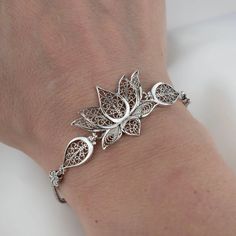 The serenity of Spirit Filigree Sterling Silver Lotus Flower Woman Link Bracelet - Handcrafted Sterling Silver Jewelry Revel in Our Meticulously Handcrafted Filigree Lotus Bracelet Honoring the bloom's symbol of spiritual serenity through masterful artistry. Graceful sterling silver filigree seamlessly fuses into a charming lotus motif, celebrating its essence of tranquility and enlightenment. Thoughtfully Designed for Adjustable Wear This bracelet beautifully accommodates wrists of all sizes wi Elegant Filigree Bracelet Jewelry, Silver Jewellery Design, Silver Filigree Flower Jewelry, Unique Silver Filigree Bracelet, Elegant Filigree Flower-shaped Jewelry, Luxury Silver Filigree Bracelet, Money Crown, Lotus Motif, Lotus Flower Jewelry