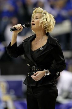 a woman singing into a microphone in front of a crowd