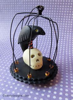 a small black bird in a cage with a piece of bread inside on a purple tablecloth