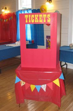 a red ticket booth sitting on top of a hard wood floor next to a blue table