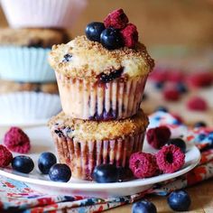 three blueberry muffins stacked on top of each other with raspberries