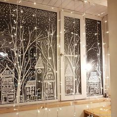 the window is decorated with christmas lights and paper cutouts, which look like cityscapes