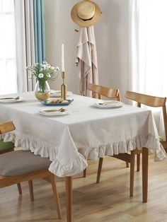 a white table cloth with ruffles and plates on it in front of a window