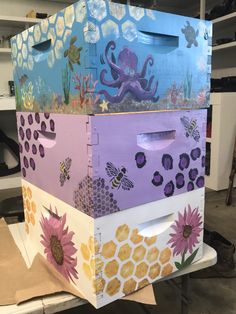 the boxes are decorated with flowers, bees and an octopus in purples and yellows