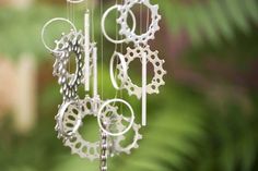 a wind chime hanging from the ceiling in front of some plants and trees with green leaves