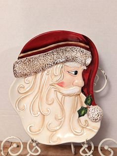 a santa clause figurine sitting on top of a wooden shelf next to a white wall