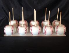 six baseballs are arranged on a white tray with wooden sticks sticking out of them