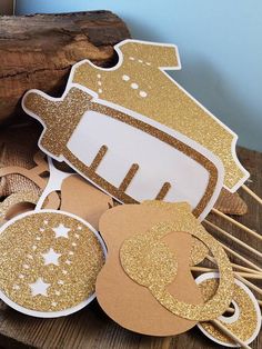 some gold glittered paper cutouts are sitting on a wooden table