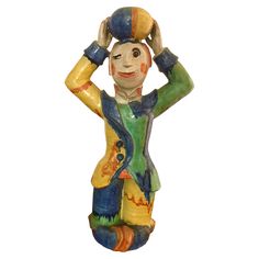 a ceramic figurine is holding a basketball ball on his head and wearing a hat