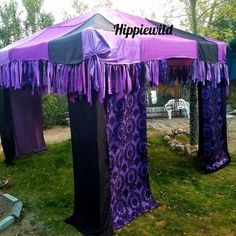 a purple and black tent sitting on top of a lush green field