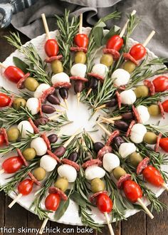 a platter with skewered olives, tomatoes, and meat on them