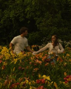 a man and woman holding hands in a field of flowers