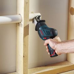 a man holding a cordless drill in his right hand and drilling holes on the wall