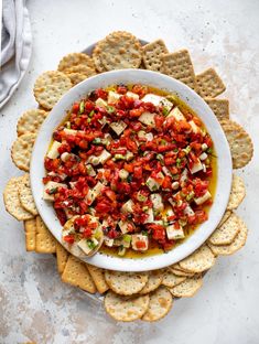 a white bowl filled with tomatoes and crackers