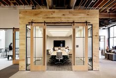 an open meeting room with glass doors leading to two people sitting at a table in front of them