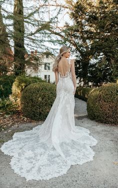 a woman in a white wedding dress standing on the ground with her back to the camera