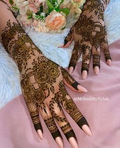 two hands with henna designs on them and flowers in the middle one is holding a bridal bouquet