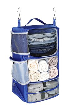 an open blue hanging organizer with folded clothes and towels in it on a white background